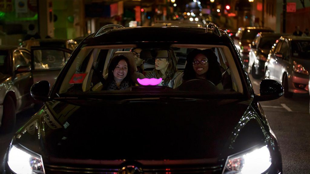 Passengers inside a car with Lyft's brand sign